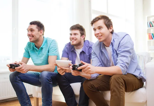 Улыбающиеся друзья, играющие в видеоигры дома — стоковое фото