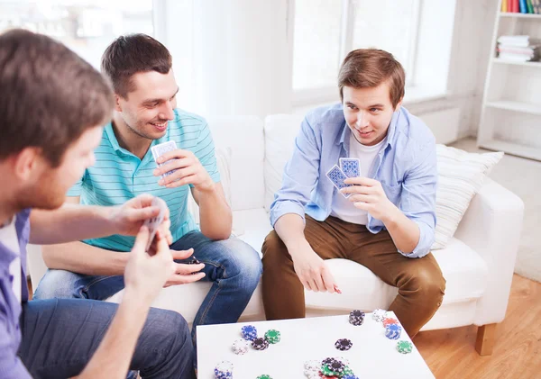 Три улыбающихся друга-мужчины играют дома в карты — стоковое фото