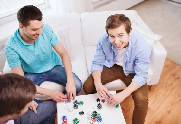 Drei lächelnde männliche Freunde beim Kartenspielen zu Hause — Stockfoto