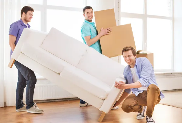 Smiling friends with sofa and cardboard boxes — Stock Photo, Image