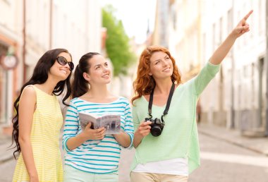 smiling teenage girls with city guide and camera clipart