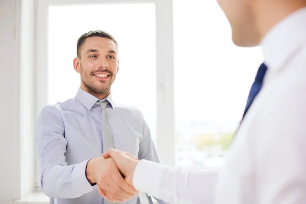 Due uomini d'affari sorridenti che si stringono la mano in ufficio — Foto Stock