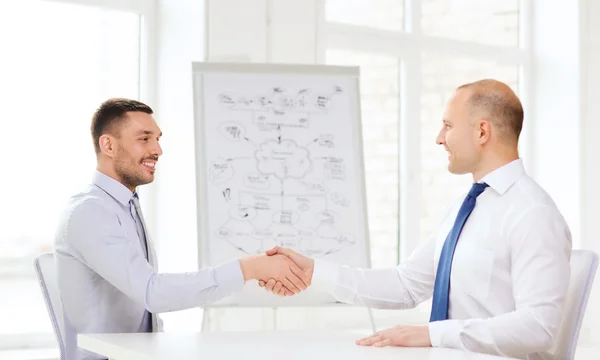 Two smiling businessmen shaking hands in office — Stock Photo, Image