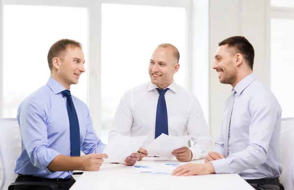 Homens de negócios sorridentes com papéis no cargo — Fotografia de Stock