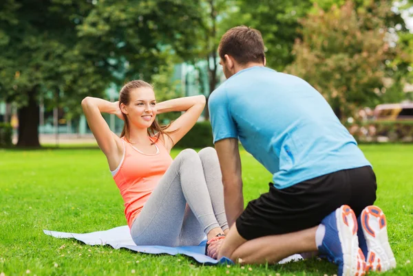 Sonriente mujer haciendo ejercicios en la estera al aire libre — Foto de Stock