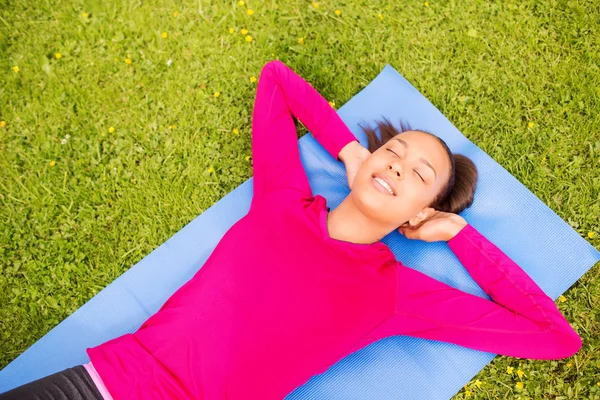 Mulher sorrindo fazendo exercícios no tapete ao ar livre — Fotografia de Stock