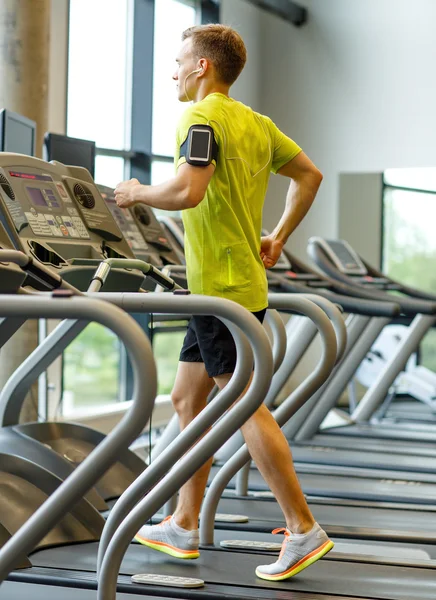 Mann med smarttelefon som trener på tredemølle i gymsalen – stockfoto