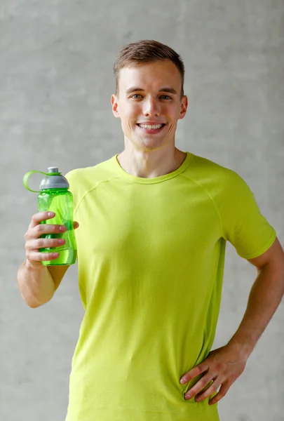 Lächelnder Mann mit Wasserflasche in Turnhalle — Stockfoto