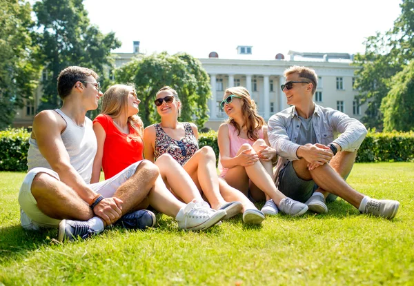 Grupa przyjaciół uśmiechający się na zewnątrz siedzi w parku — Zdjęcie stockowe