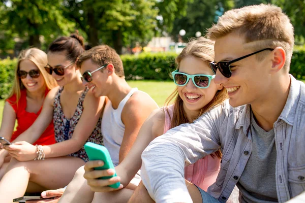 Amigos sonrientes con teléfono inteligente haciendo selfie — Foto de Stock