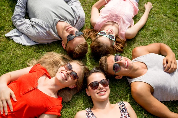 Groupe d'amis souriants couchés sur l'herbe à l'extérieur — Photo