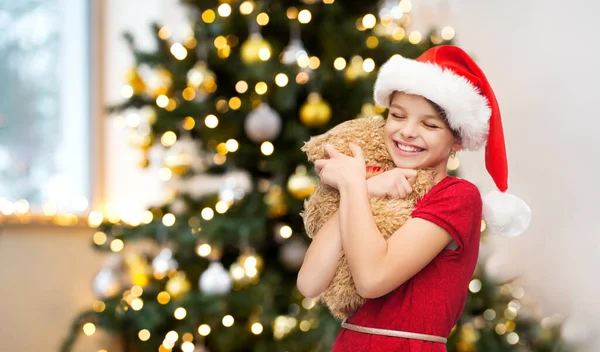 Oyuncak ayı ile santa yardımcı şapkalı kız gülümseyerek — Stok fotoğraf