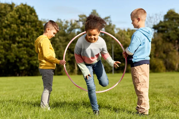 Niños felices jugando con hula hoop en el parque —  Fotos de Stock