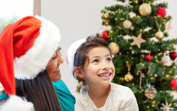 Happy mother and little girl in santa hats at home Royalty Free Stock Photos