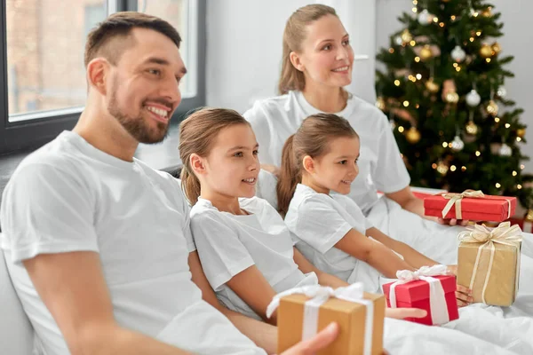 Happy family with christmas gifts in bed at home — Stock Photo, Image