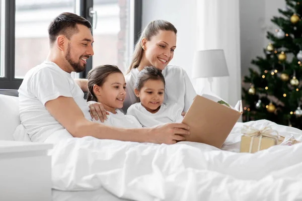 Libro de lectura familiar feliz en la cama en Navidad — Foto de Stock