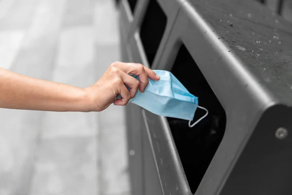 Primo piano di mano gettando maschera usata nel cestino — Foto Stock