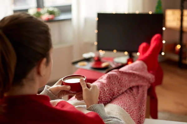 Женщина смотрит телевизор и пьет кофе на Рождество — стоковое фото