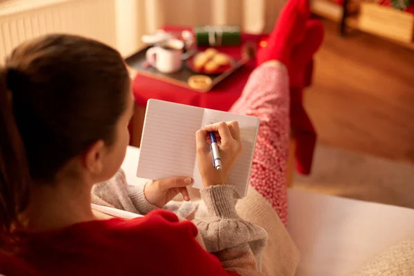 Frau schreibt an Weihnachten zu Hause an Notizbuch — Stockfoto