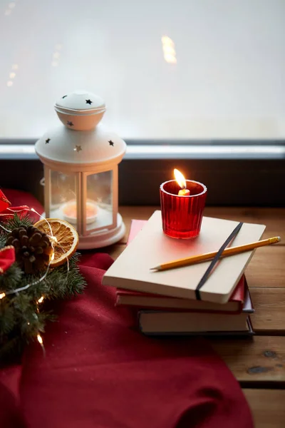 Grinalda de Natal, livros, vela, lanterna na janela — Fotografia de Stock