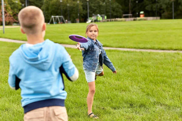 Niños felices jugando con disco volador en el parque —  Fotos de Stock