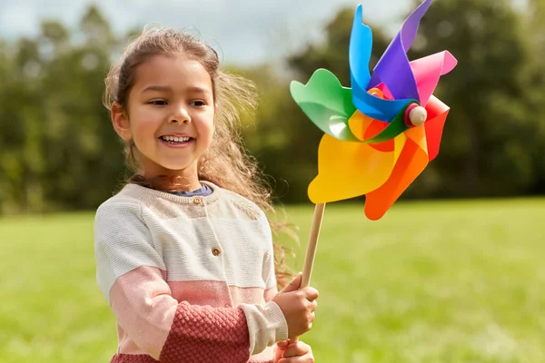 Szczęśliwa dziewczynka z pinwheel gra w parku — Zdjęcie stockowe