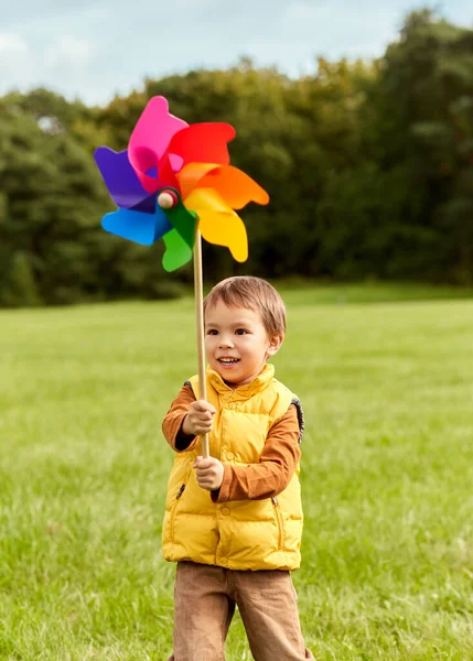 Szczęśliwy mały chłopiec z pinwheel zabawy w parku — Zdjęcie stockowe