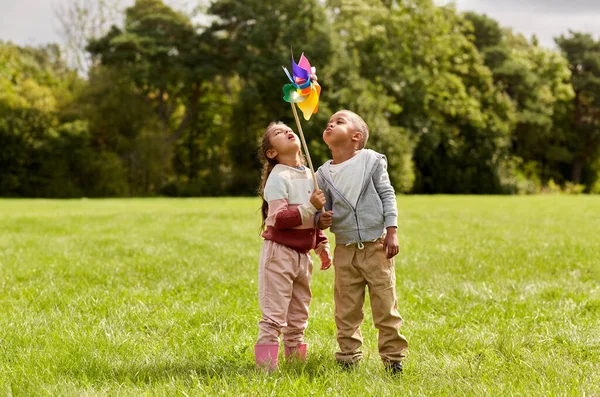 Gelukkig kinderen met pinwheel hebben plezier op park — Stockfoto