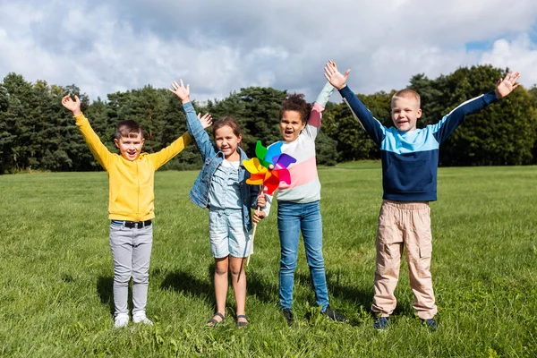 Crianças felizes com pinwheel se divertindo no parque — Fotografia de Stock