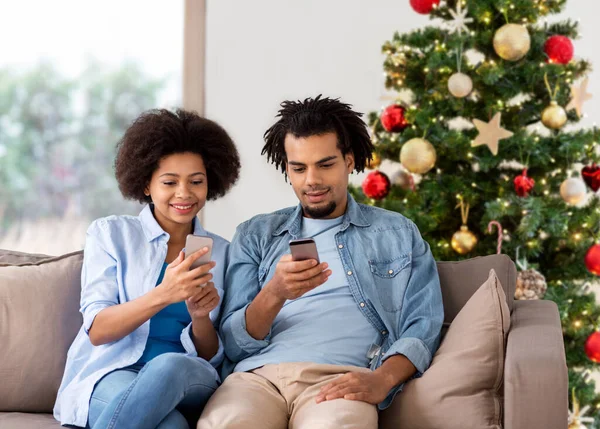 Szczęśliwa para z smartfonów w domu na Boże Narodzenie — Zdjęcie stockowe