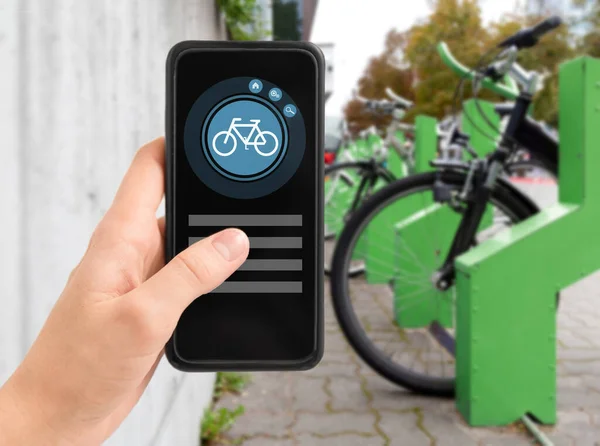 Hand with phone at electric bike charging station — Stock Photo, Image