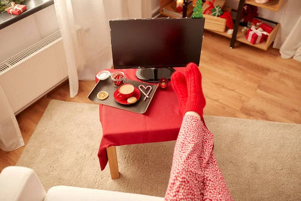 圣诞节那天，穿红袜的脚在家里的桌子上 — 图库照片