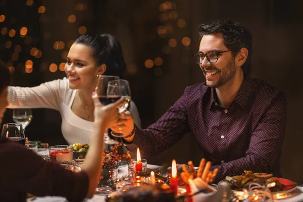 Счастливые друзья пьют вино на рождественской вечеринке — стоковое фото