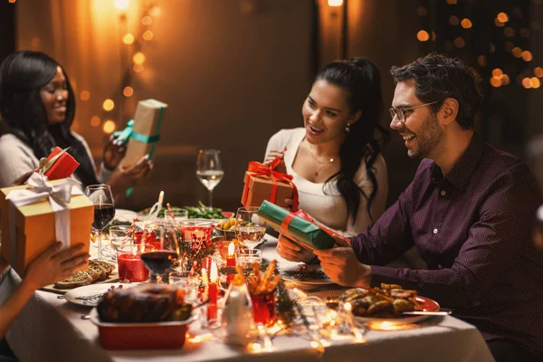 Amigos felizes dando presentes de Natal em casa — Fotografia de Stock