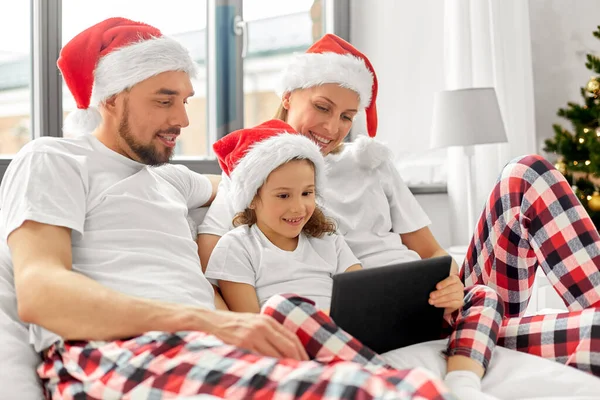 Šťastná rodina s tabletem PC v posteli na Vánoce — Stock fotografie