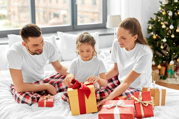 Ευτυχισμένη οικογένεια με χριστουγεννιάτικα δώρα στο κρεβάτι στο σπίτι — Φωτογραφία Αρχείου