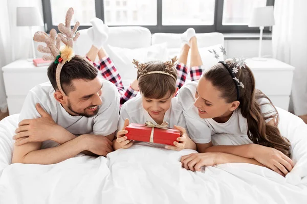 Family with christmas gift in bed in morning — Stock Photo, Image