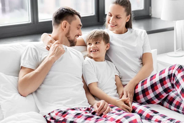 Счастливая семья в пижаме в постели по утрам — стоковое фото