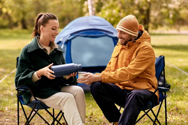 Casal feliz com thermos derramando chá no acampamento tenda — Fotografia de Stock