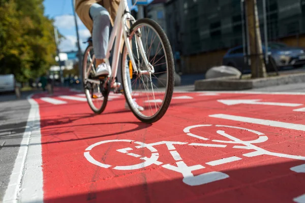 Жінка їде на велосипеді вздовж дороги червоного велосипеда в місті Стокове Зображення