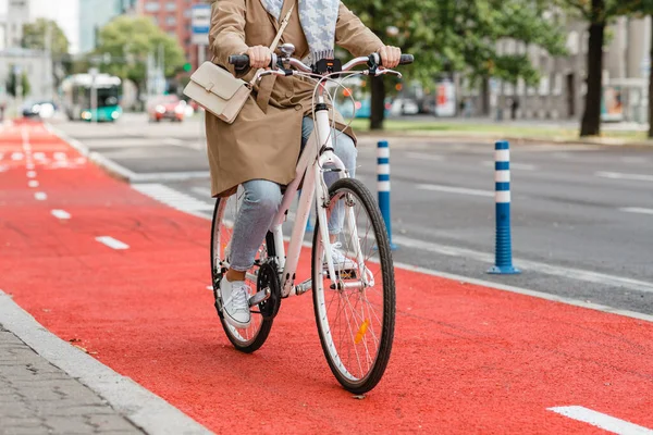 Kobieta jazda na rowerze wzdłuż czerwonego pasa rowerowego w mieście — Zdjęcie stockowe