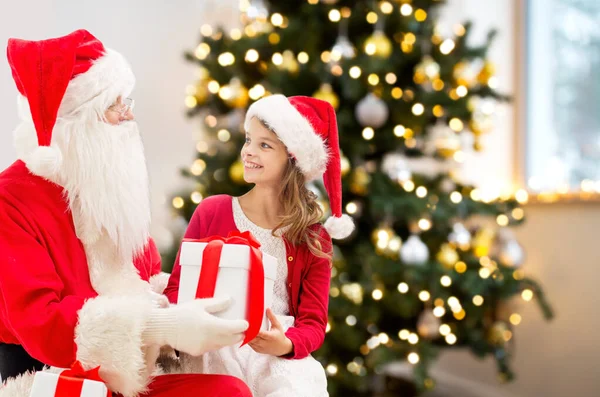 Улыбающаяся девушка с Санта-Клаусом и подарками дома — стоковое фото
