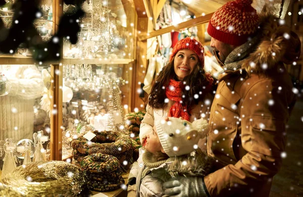 Ευτυχισμένη οικογένεια που αγοράζει στεφάνι στη χριστουγεννιάτικη αγορά — Φωτογραφία Αρχείου