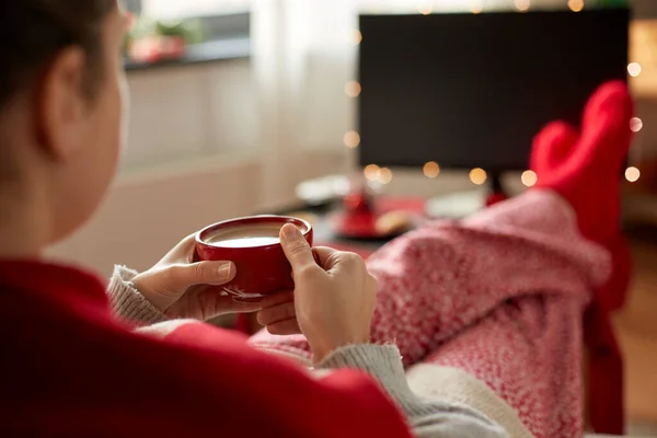 Женщина смотрит телевизор и пьет кофе на Рождество — стоковое фото