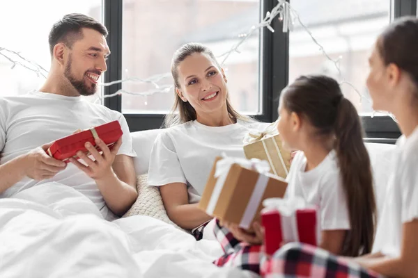 Happy family with christmas gifts in bed at home — Stock Photo, Image