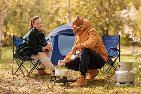 Çadır kampında bira içip yemek pişiren çift. — Stok fotoğraf