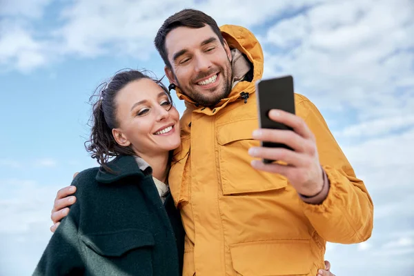 Paar mit Smartphone am Herbststrand — Stockfoto
