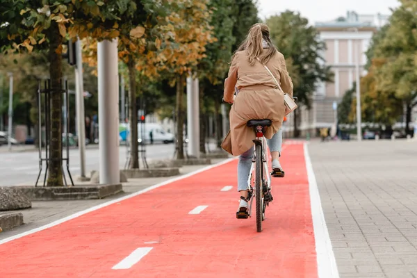 城市里骑自行车沿着红色自行车道行驶的妇女 — 图库照片