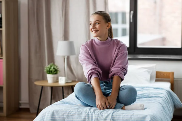 Heureuse fille souriante assise sur le lit à la maison — Photo