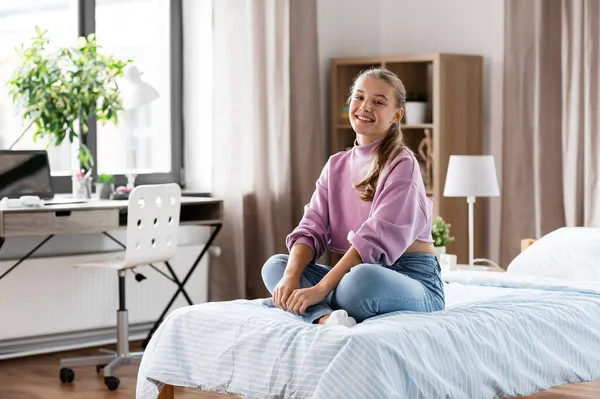 Šťastná usměvavá dívka sedí doma na posteli — Stock fotografie